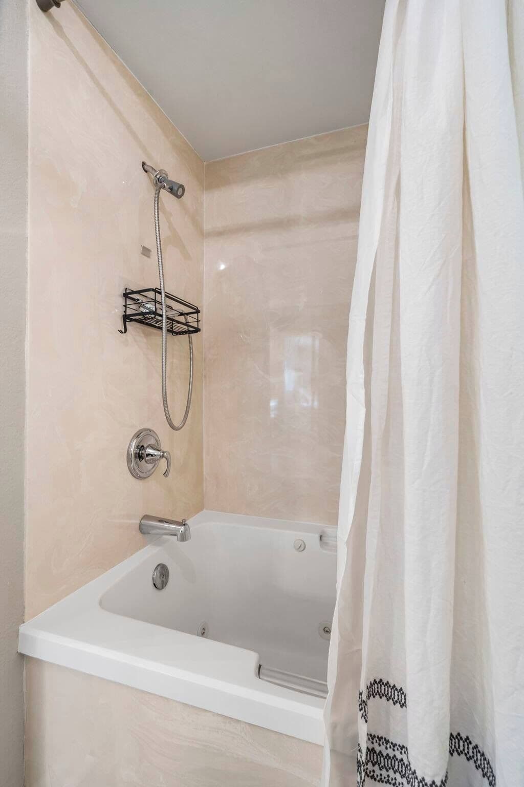 Un baño con bañera, ducha y un perchero para toallas.