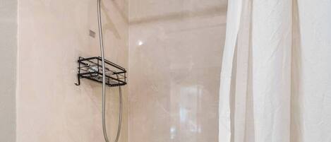 A bathroom with a bathtub, a shower, and a towel rack.