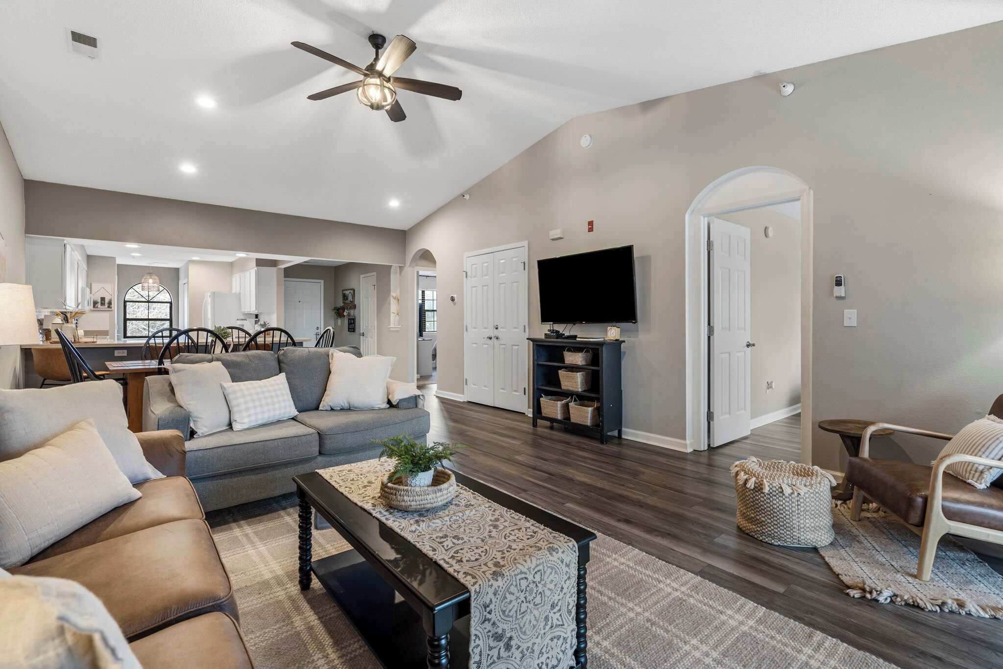 A spacious living room with a grey sofa, a coffee table, and a television.