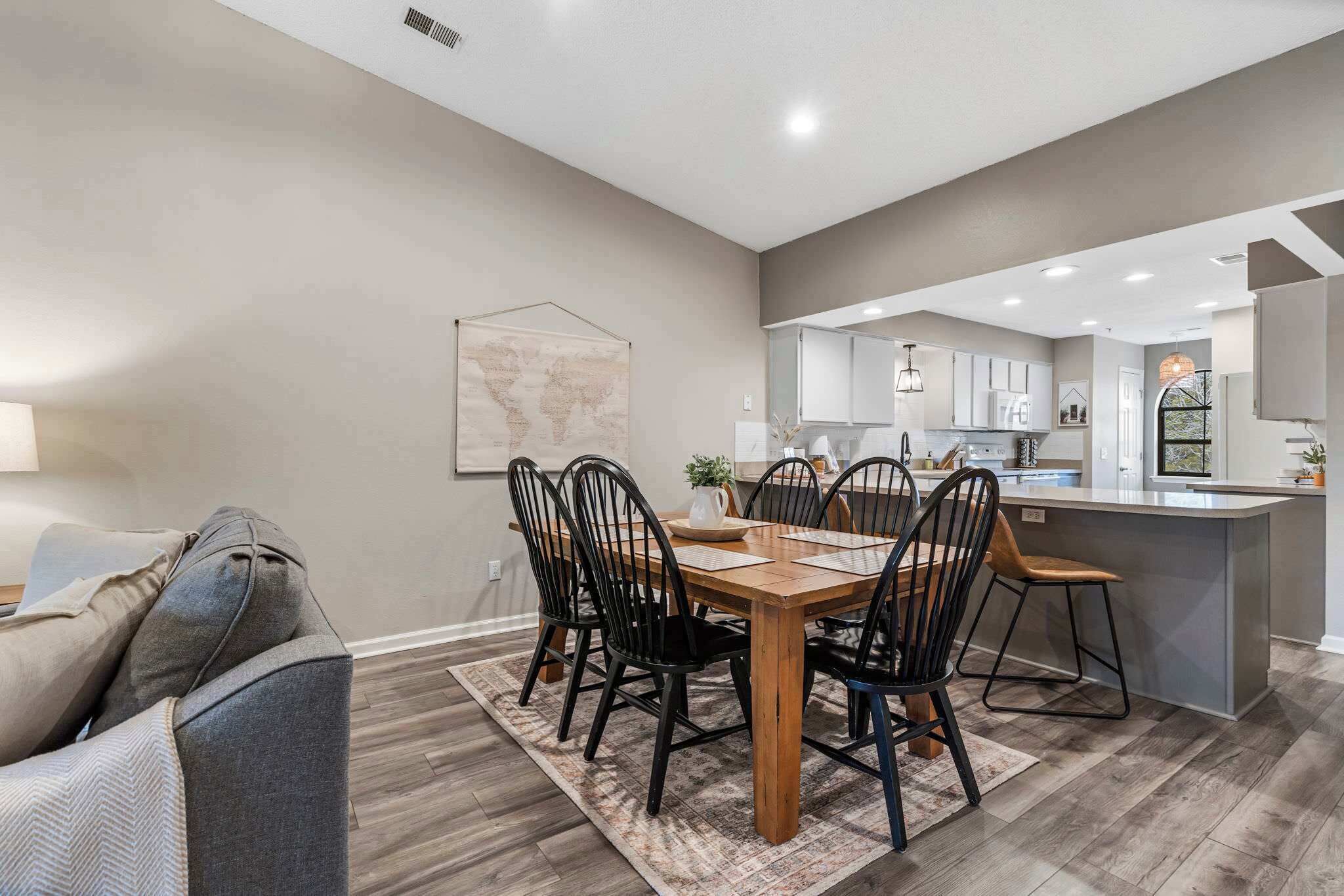 A modern kitchen with white cabinets, a central island, and a dining area with a wooden table and black chairs.