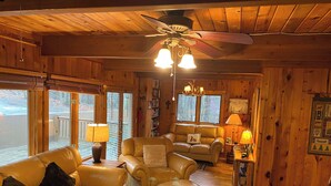 Interior acogedor de una cabaña con techo de madera, sofás de cuero, una mesa de centro y una chimenea.