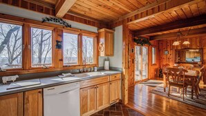 Una cabaña de madera con cocina que cuenta con una isla grande, armarios de madera y una zona de comedor con mesa y sillas.
