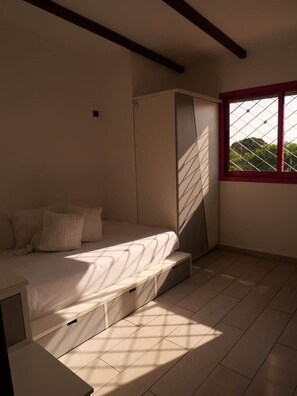 A bedroom with a bed, a wardrobe, and a window with a view. - Appartement cozy en résidence (Libreville)