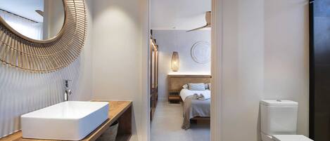 A modern bathroom with a large mirror, a wooden vanity, a white sink, and a toilet.