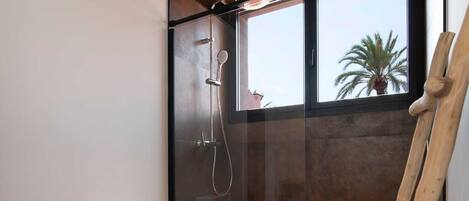 Un baño moderno con ducha acristalada, inodoro blanco y escalera de madera.