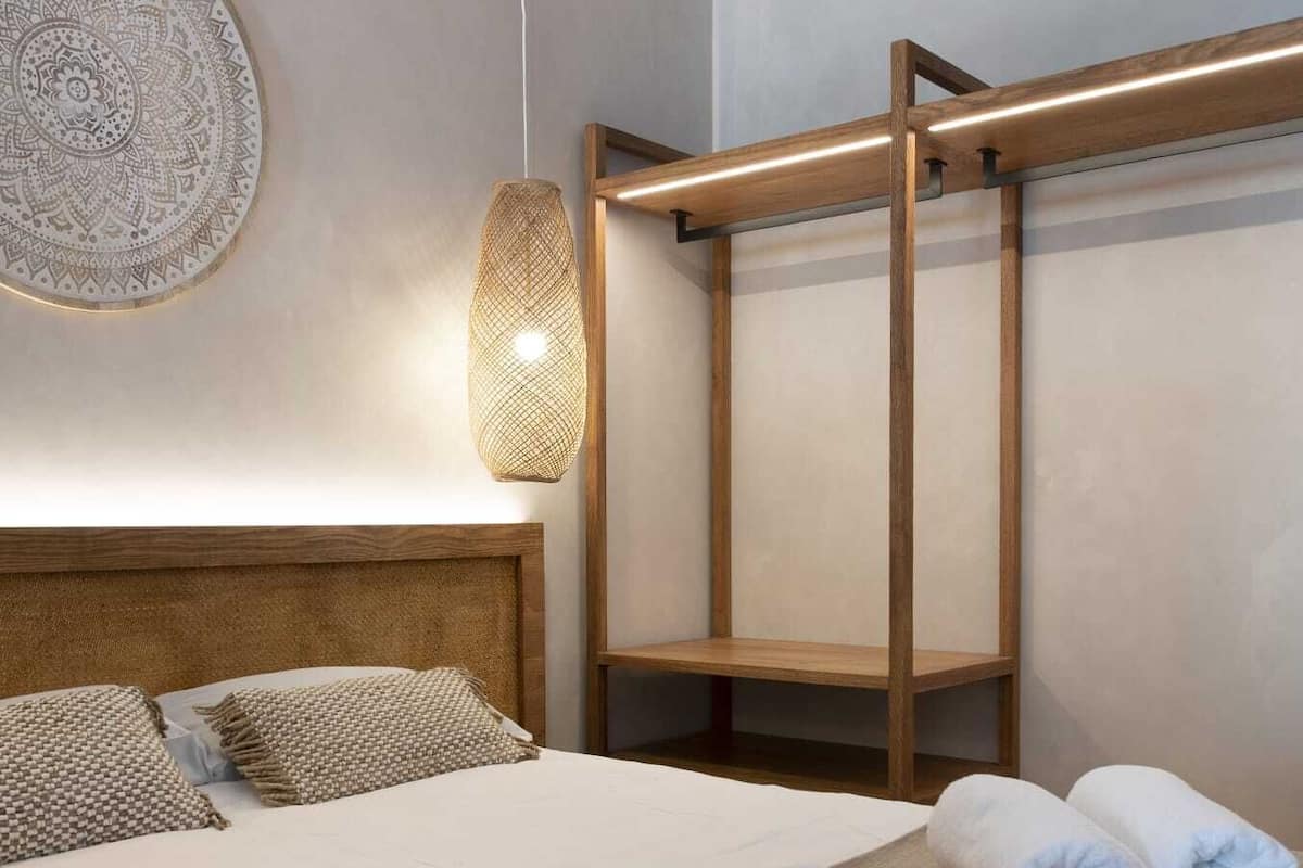 A modern hotel room with a large bed, a wooden headboard, a wall-mounted circular decorative piece, and a hanging light fixture.