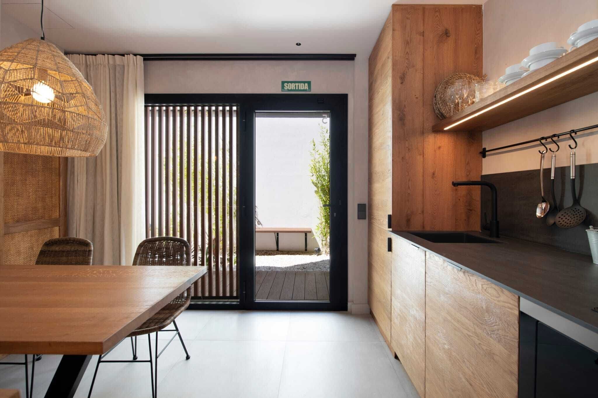 Una cocina moderna con armarios de madera, un lavaplatos integrado y un colgador para ollas.