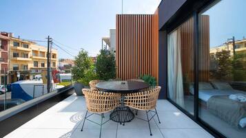 Een modern balkon met een ronde tafel en rieten stoelen, met uitzicht op een stadsgezicht.