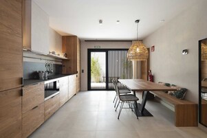Una cocina moderna con armarios de madera, encimera negra y una zona de comedor con mesa y sillas de madera.