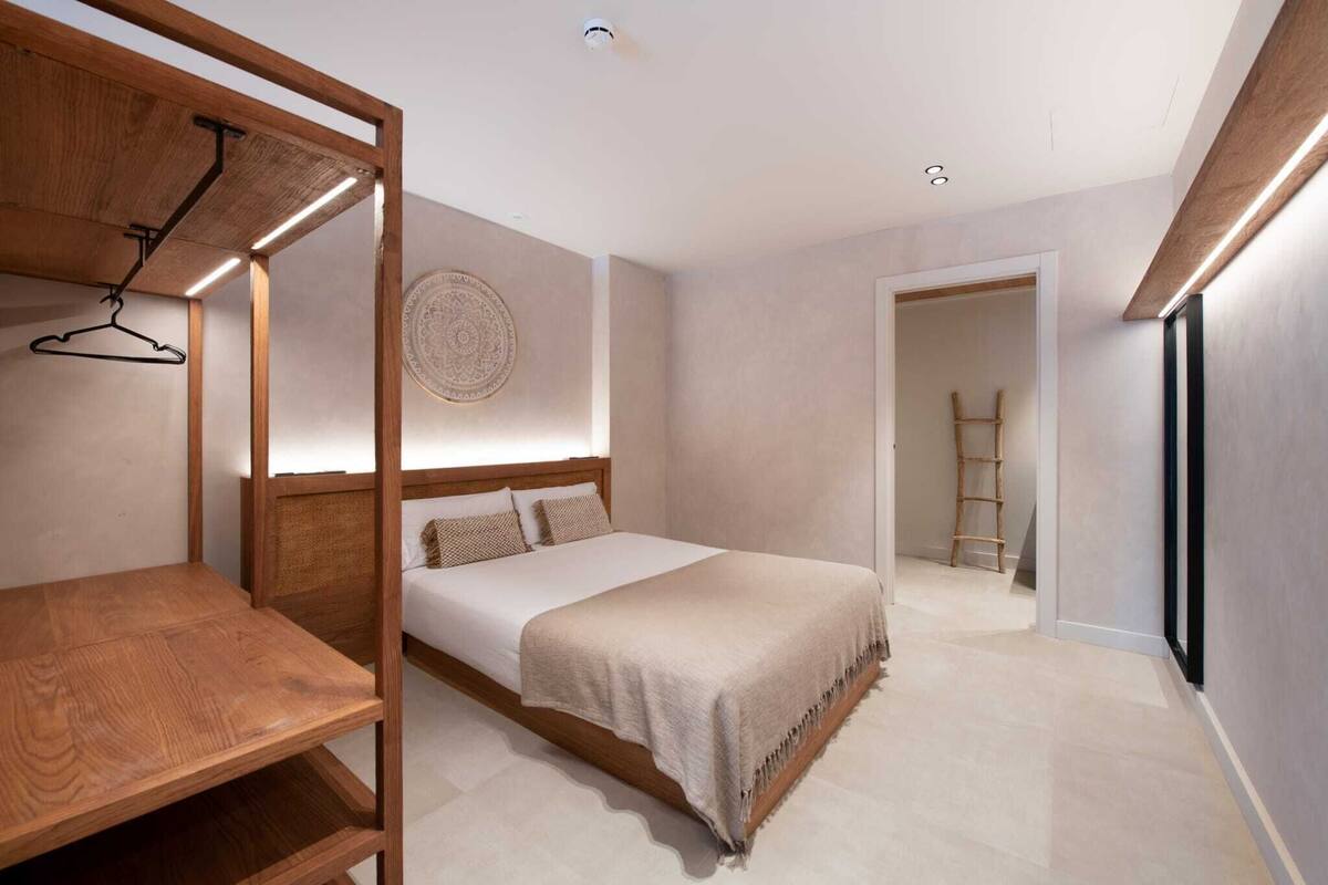 A modern bedroom with a wooden bed frame, a bedside table, and a hanging garment rack.