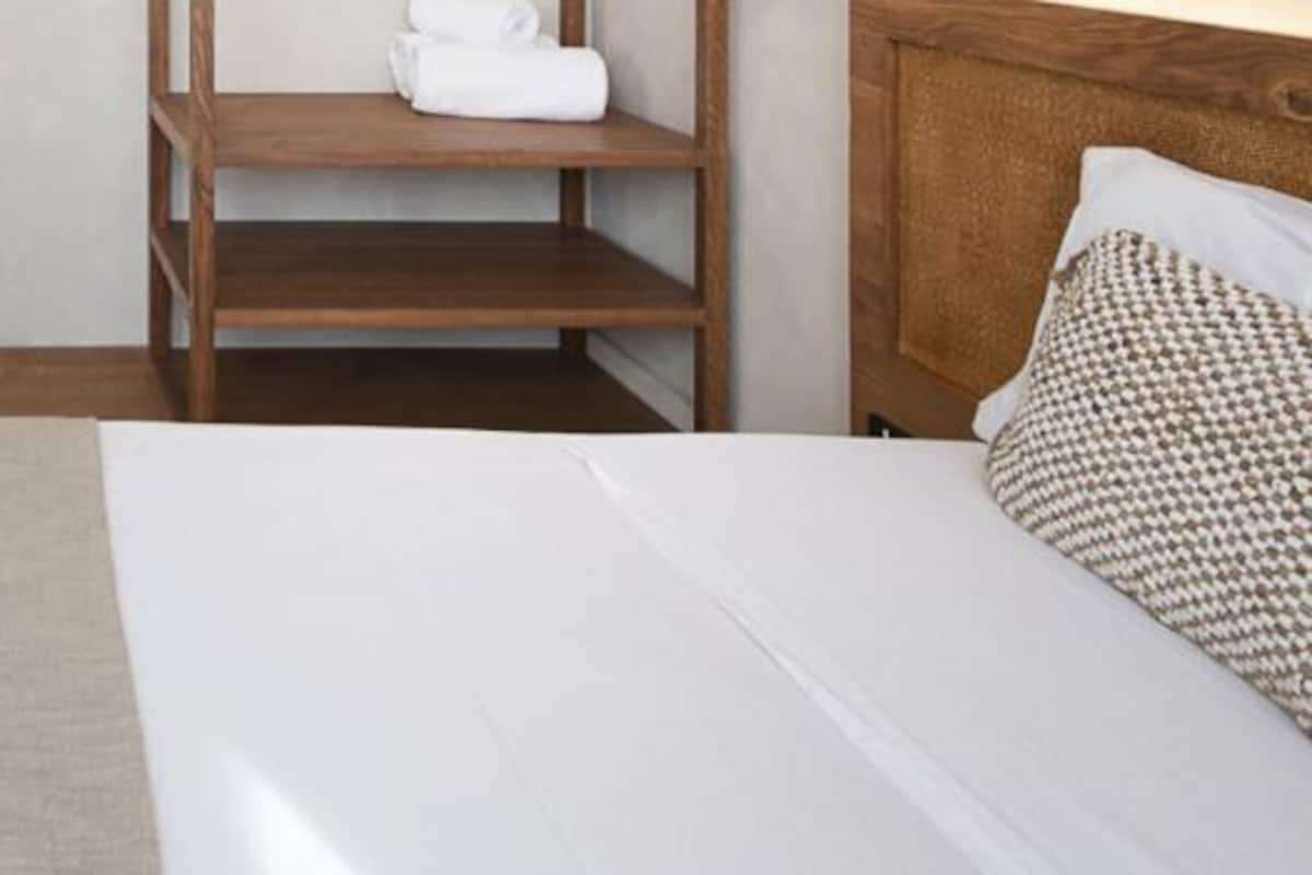 A hotel room with a bed, wooden shelves, and a headboard.