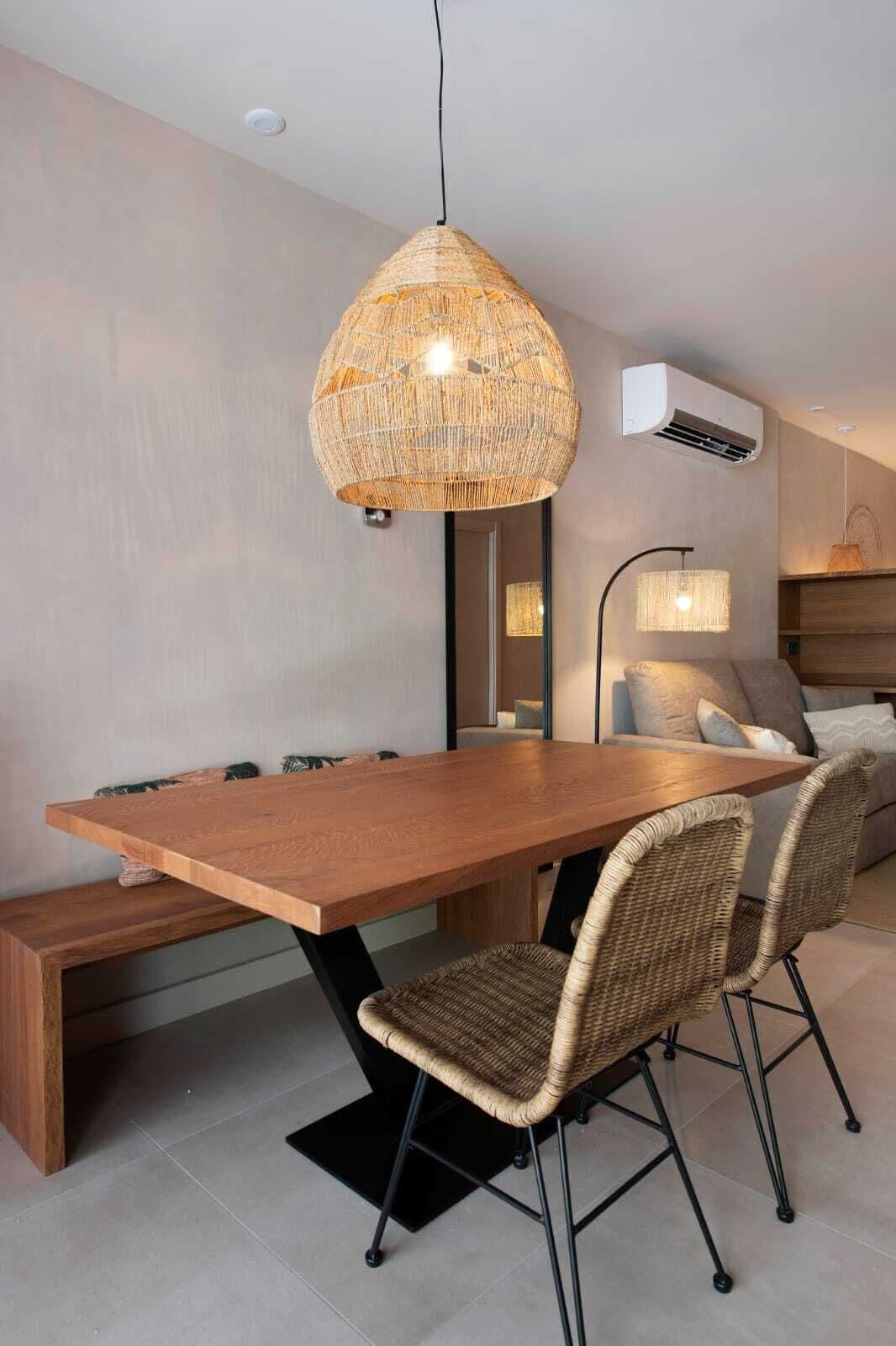 Een moderne eetruimte met een houten tafel, rieten stoelen en een geweven hanglamp.