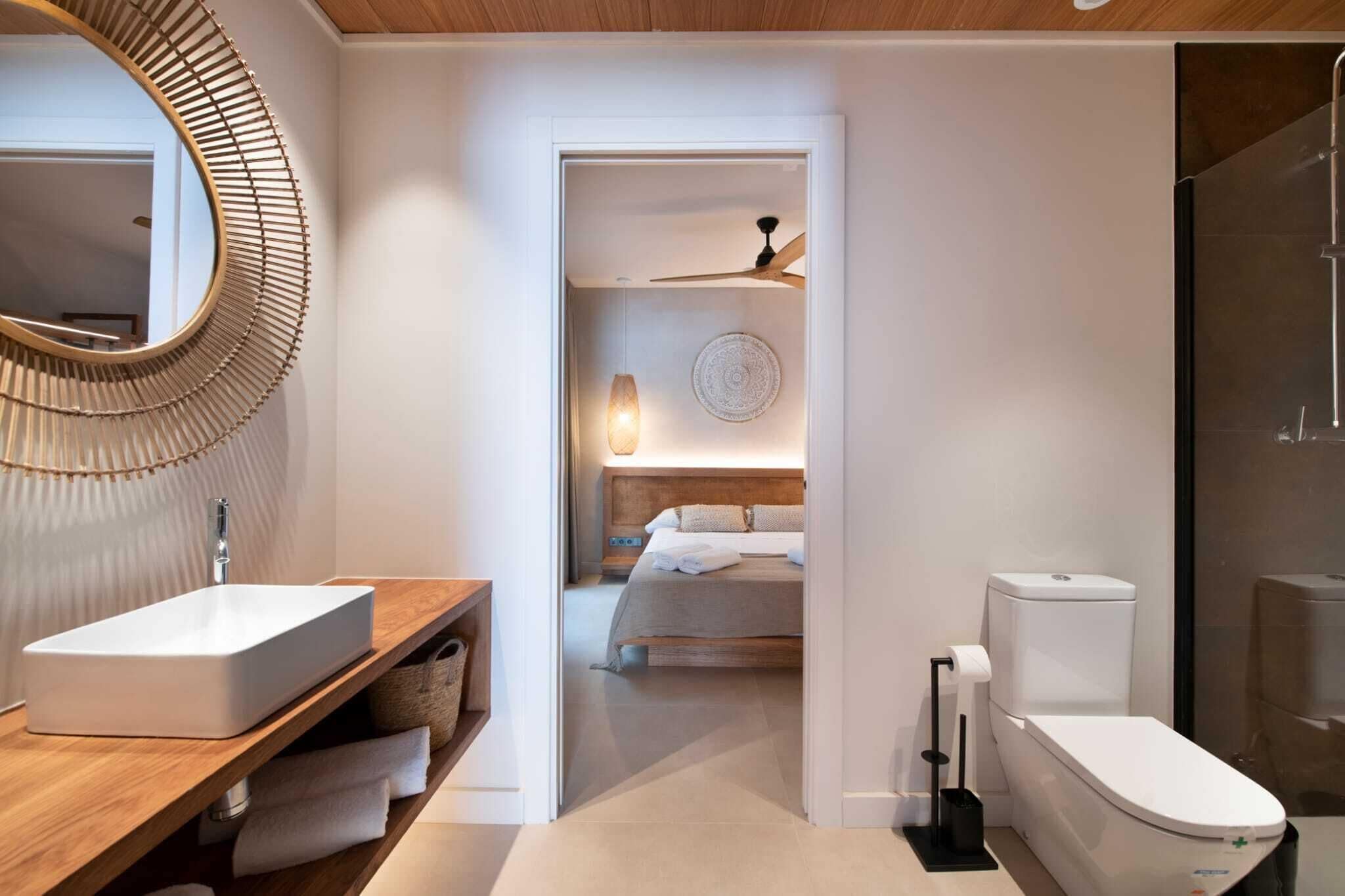 A modern bathroom with a wooden vanity, a large mirror, a toilet, and a shower area.