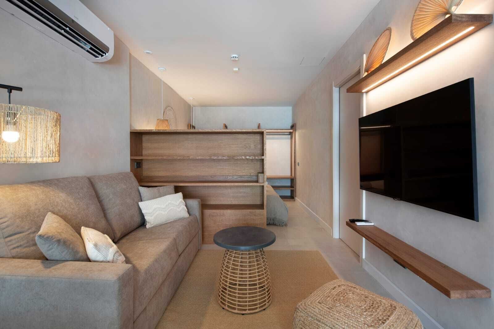 A modern living room with a sofa, a coffee table, and a TV mounted on the wall.