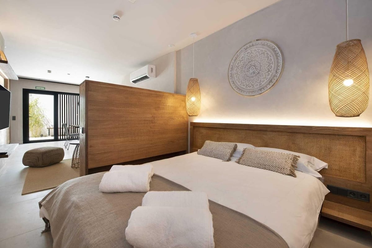 A modern hotel room with a large bed, a wooden headboard, a wall-mounted circular design, and a balcony with a view.