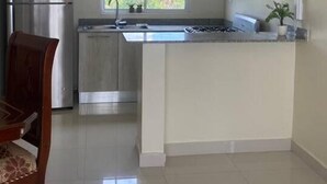 Een moderne keuken met een centraal eiland, roestvrijstalen apparatuur en een raam dat voor daglicht zorgt.