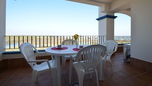 Varanda com mesa e cadeiras, vista para a praia.