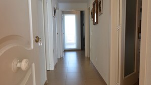 A hallway with white doors, a tiled floor, and a view into another room. - Espigón Poniente 7 - Two Bedroom Apartment, Sleeps 5 (Punta del moral)