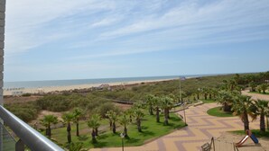 A view from a balcony overlooking a beach, palm trees, and a paved walkway. - Espigón Poniente 7 - Two Bedroom Apartment, Sleeps 5 (Punta del moral)