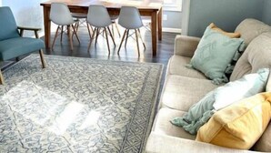 Un salon comprenant une table à manger, des chaises, un canapé et un tapis à motifs.