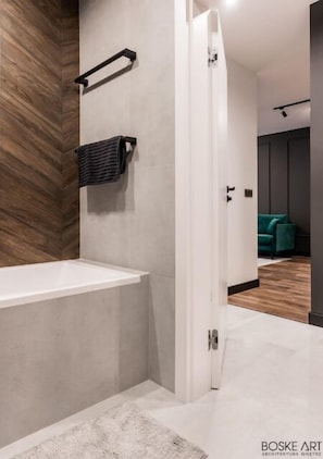 Ein modernes Badezimmer mit einer Badewanne, einem Handtuchhalter und einer Wand mit Holzverkleidung.