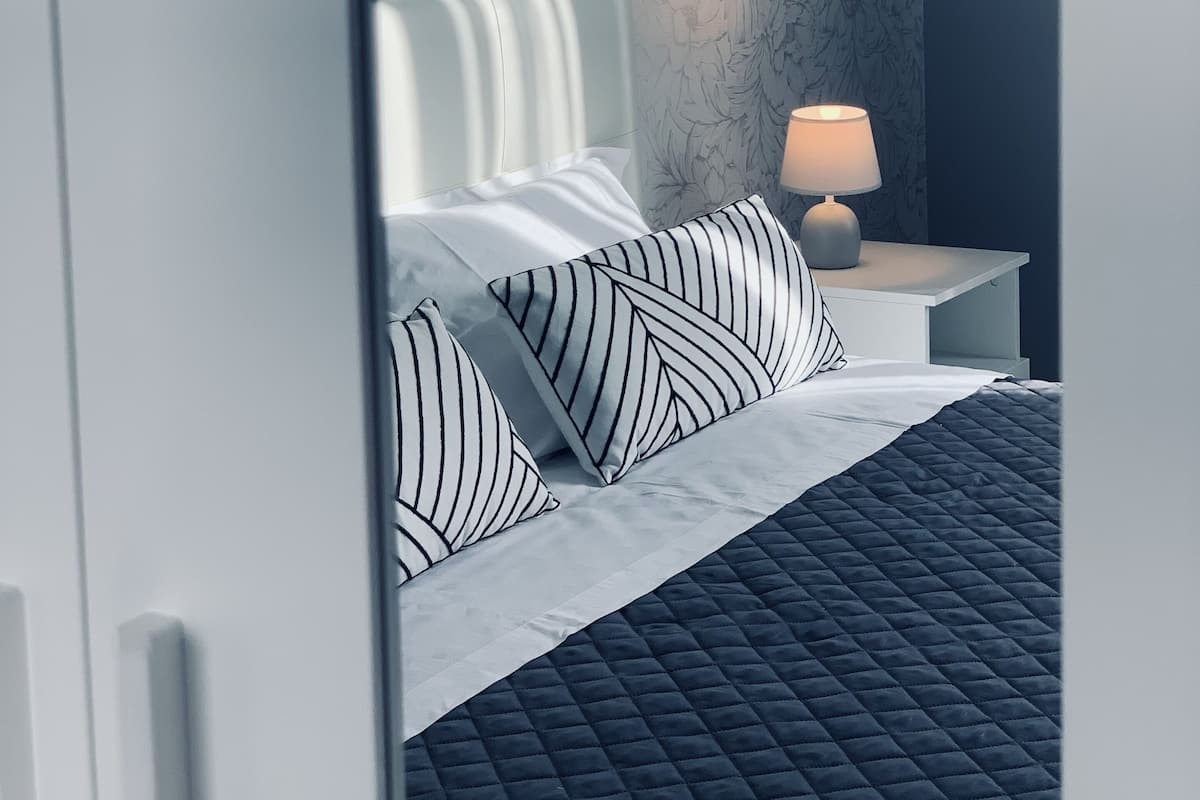 Ein modernes Schlafzimmer mit einem Bett, Kissen, einem Nachttisch und einer Lampe.