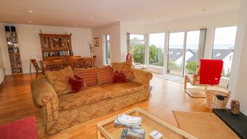 A spacious living room with a large sofa, a coffee table, and a dining area with chairs and a table.