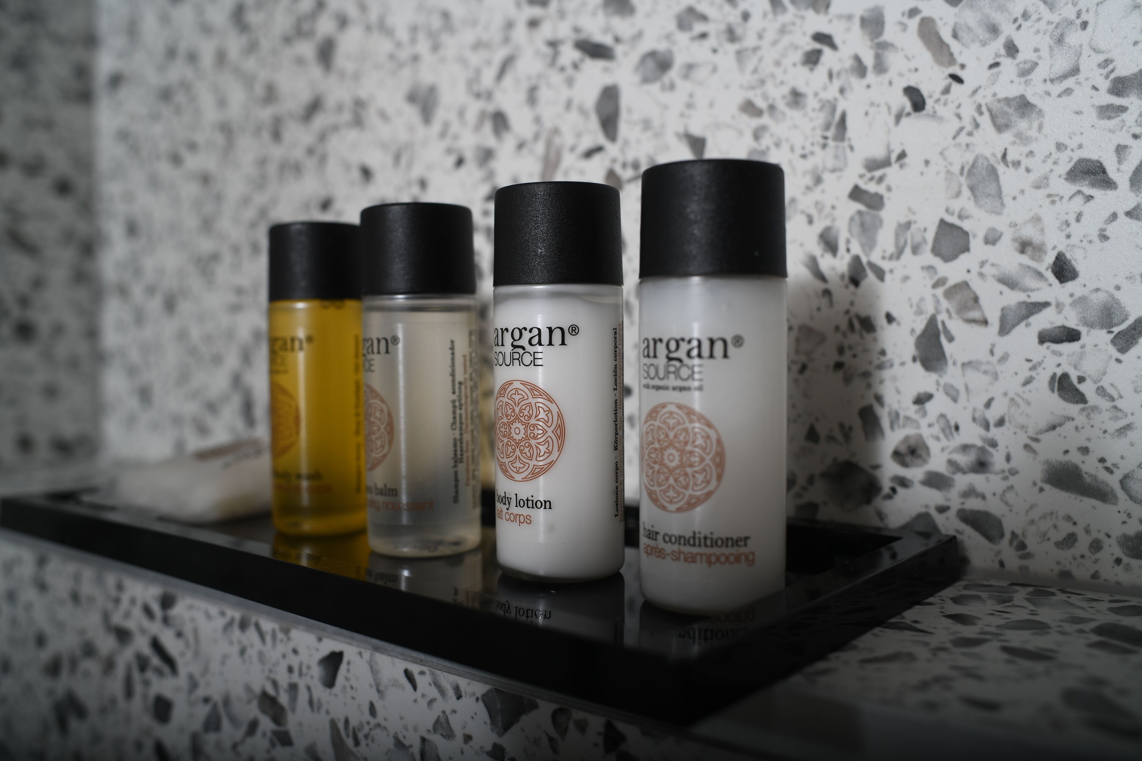 Una estantería con cuatro botellas de loción corporal y acondicionador para el cabello Argan.