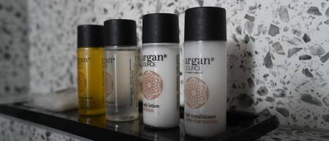 Una estantería con cuatro botellas de loción corporal y acondicionador para el cabello Argan.