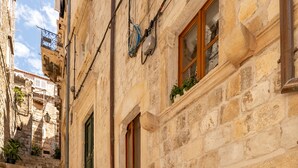A stone staircase leading to a room with a bed, a window with plants, and a view of the street. - Live Laugh Love Dubrovnik luxury rooms (Dubrovnik)