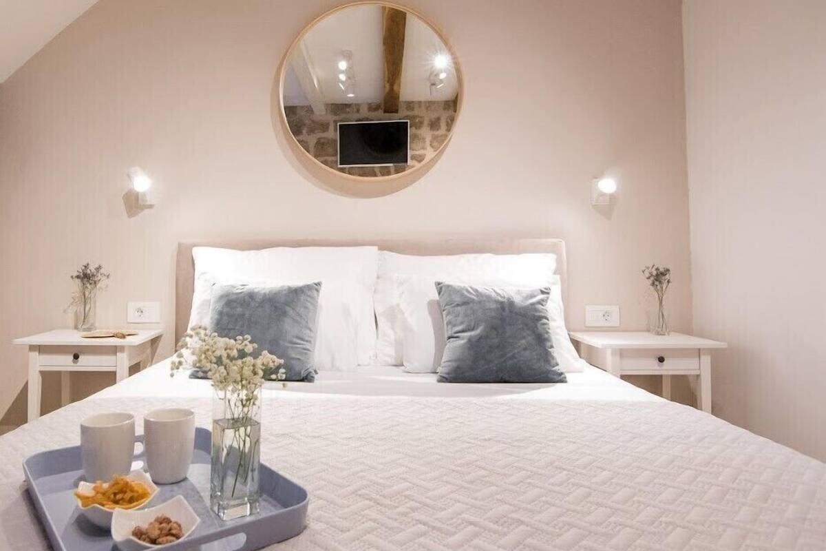 Une chambre à coucher avec un grand lit, deux tables de chevet, un miroir rond et un plateau contenant de la nourriture et des boissons.