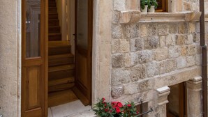 A stone building with a wooden staircase leading to an interior door. There are potted plants on the steps. - Live Laugh Love Dubrovnik luxury rooms (Dubrovnik)