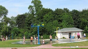 A water park with a play structure, a small building, and a wooden fence. - The Gorgeous George Beach Cottage (East Haven)
