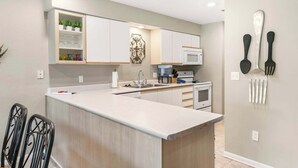 A modern kitchen with white cabinetry, a central island, and a microwave. - Golf View Escape - Holiday Hills Branson - Golf - Outdoor Pools (Branson)