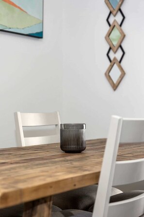 A wooden dining table with a glass candle holder in the center.