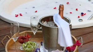 Un plateau en bois avec un bain à remous, une bouteille de champagne, des verres et des corbeilles de fruits.