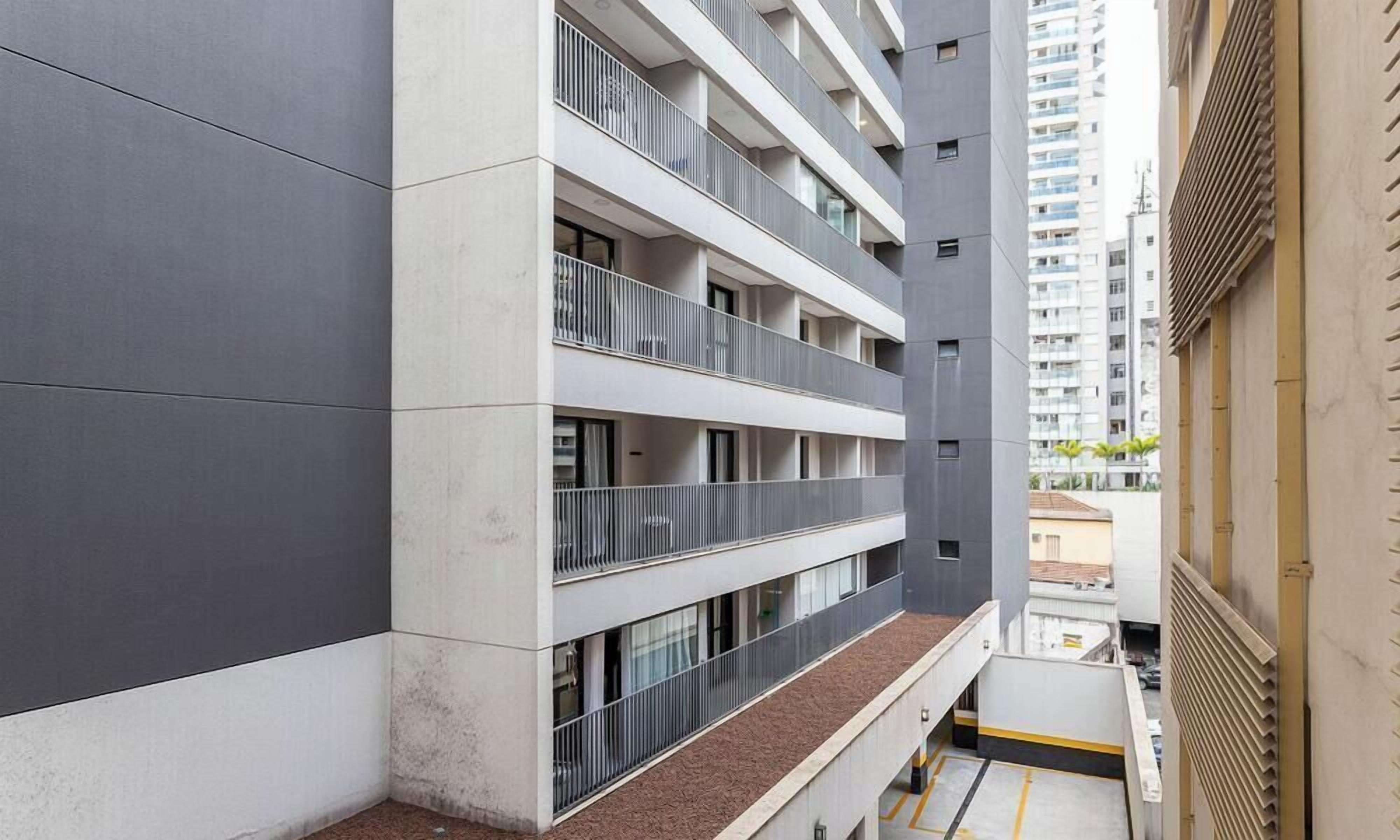 Un immeuble à plusieurs étages doté de balcons, de grandes fenêtres et d’un espace de stationnement.