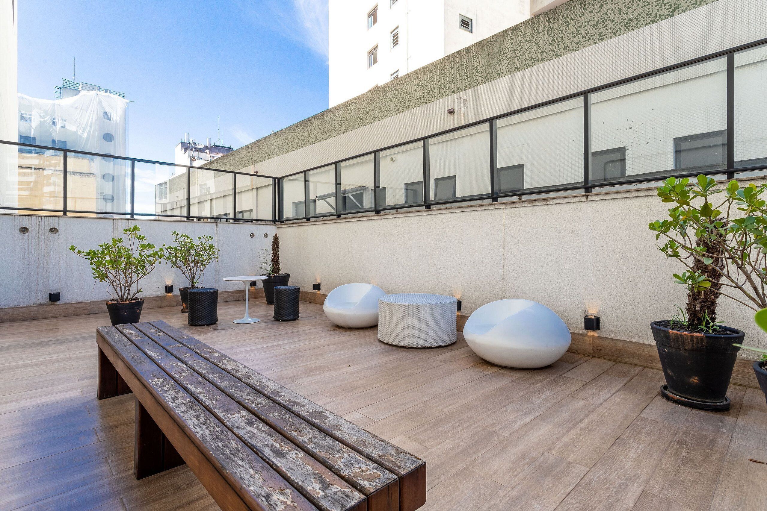 A rooftop terrace with wooden flooring, potted plants, and modern seating.