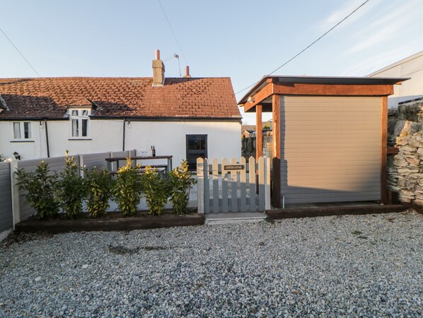 A residential property with a gravel driveway, a white house with a tiled roof, a wooden fence, and a garage. - Eventide (Plymouth)
