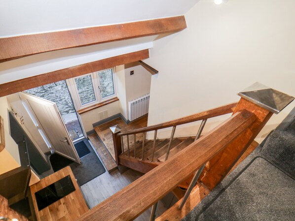 A wooden staircase with a glass railing leading to a landing. - Eventide (Plymouth)