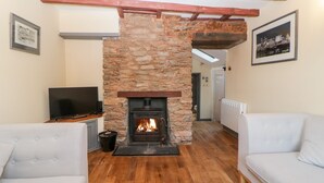 A living room with a stone fireplace, wooden flooring, and white sofas. - Eventide (Plymouth)