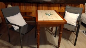 A cozy room with wooden walls and a wooden table with chairs. - Your Nomadic Room : Outremer (Marthod)