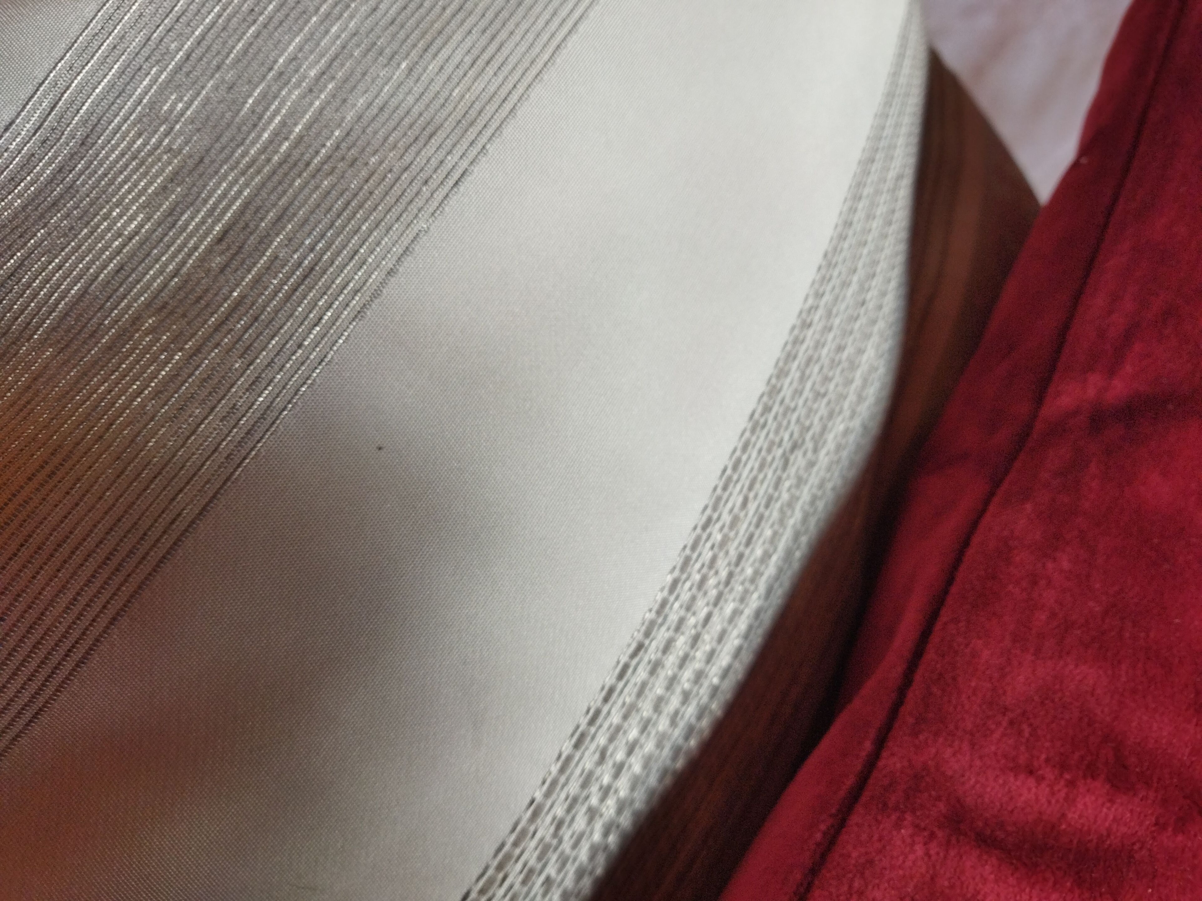 Primer plano de un tejido con textura acanalada y un borde de tela rojo.