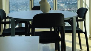 A dining area with a table and chairs, a vase on the table, and a city view through large windows. - City Apartment in Copenhagen with 1 bedrooms sleeps 4 (Copenhagen)