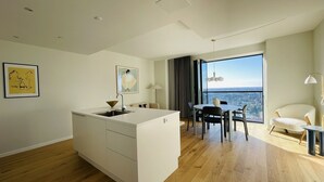 Eine moderne Wohnung mit Kücheninsel, Essbereich und großem Fenster mit Blick auf die Stadt.