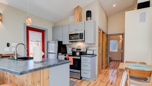 A modern kitchen with grey cabinets, a built-in microwave, and a wooden island with stools.