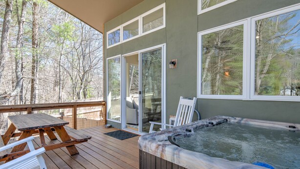 A wooden deck with a hot tub, a picnic table, and a chair.