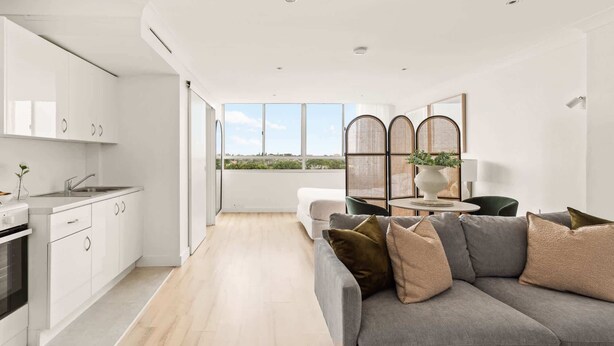 A modern kitchen with white cabinets, a built-in oven, and a window overlooking a cityscape.