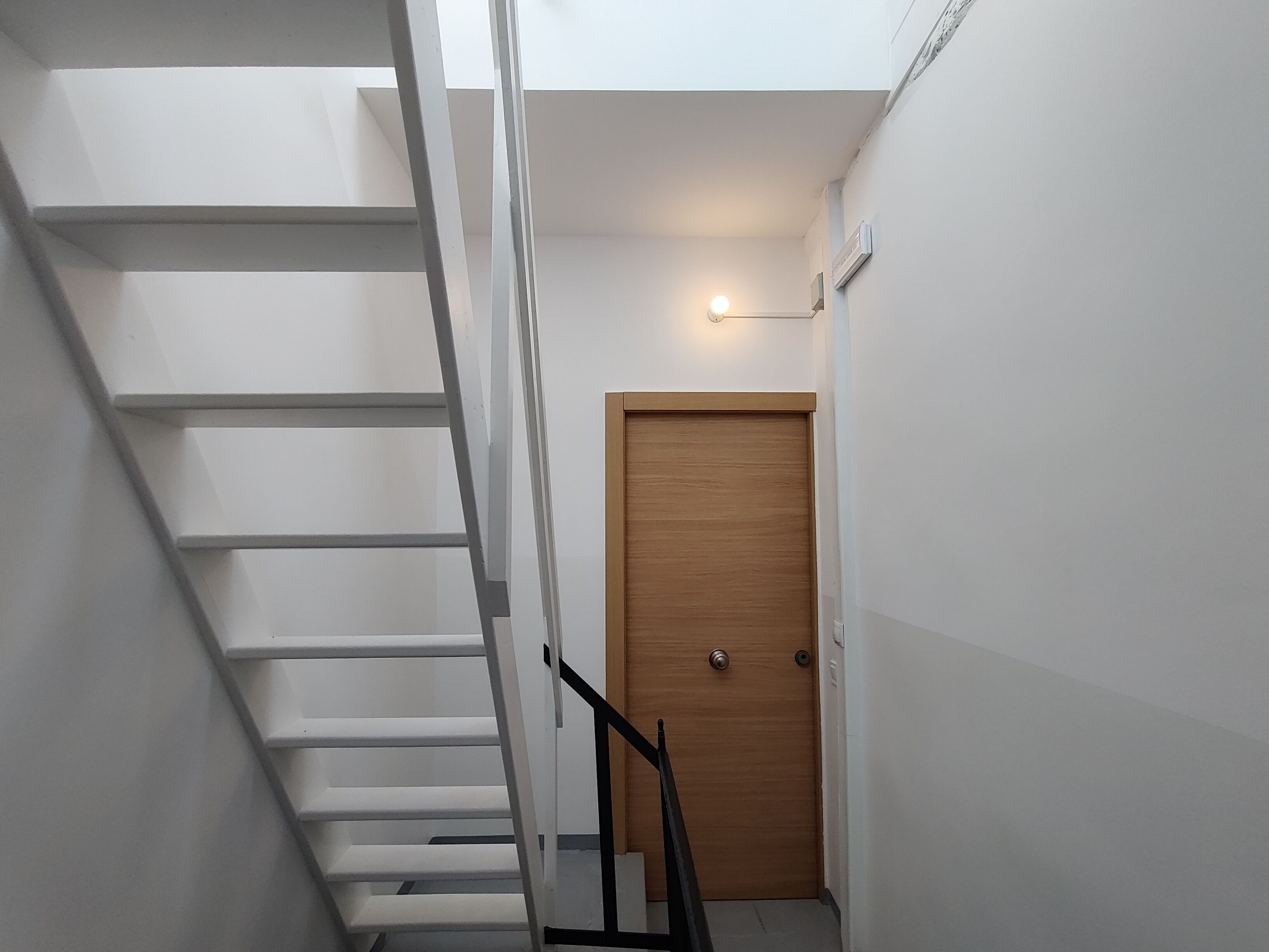A staircase with white steps and a wooden door at the bottom.