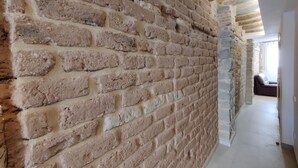 A hallway with exposed brick walls and a stone base, leading to a room with a bed and a window. - Charming Loft in the Historic Center of Manresa. (Manresa)